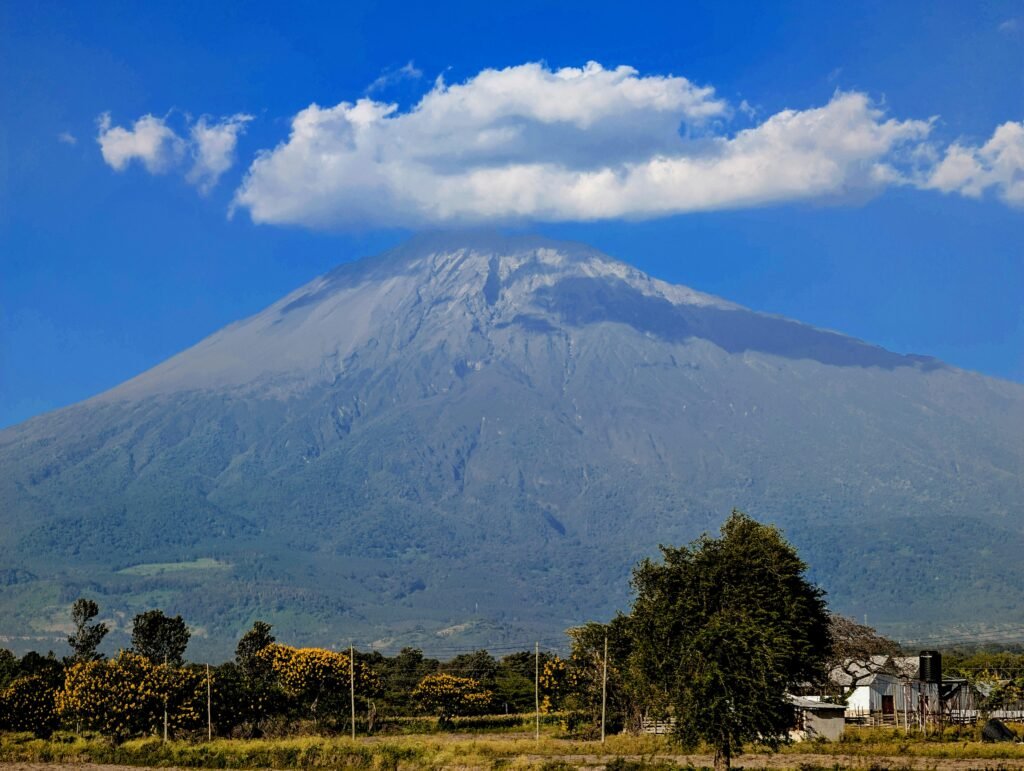 Scenic view of Mount Meru under a cloud with lush greenery, Arusha, Tanzania.